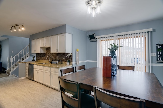 kitchen with stainless steel dishwasher, decorative backsplash, a sink, and white cabinets