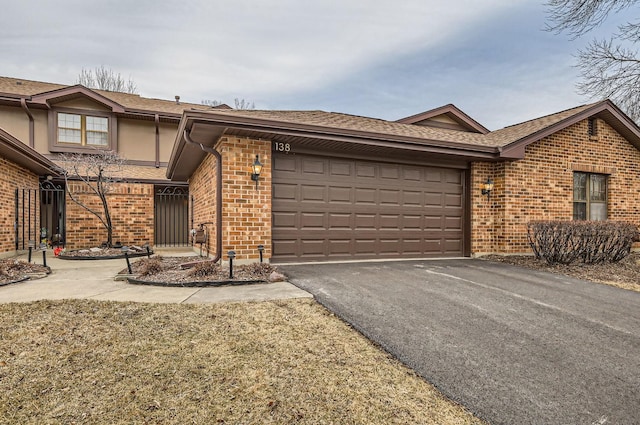 ranch-style home with aphalt driveway, brick siding, and a garage