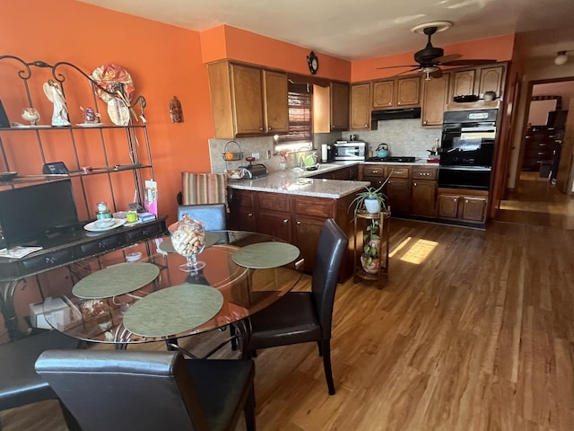 kitchen with a ceiling fan, backsplash, dark wood-style flooring, a warming drawer, and black oven