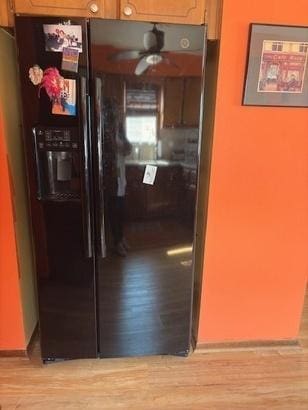 kitchen with light wood finished floors, ceiling fan, and black refrigerator with ice dispenser