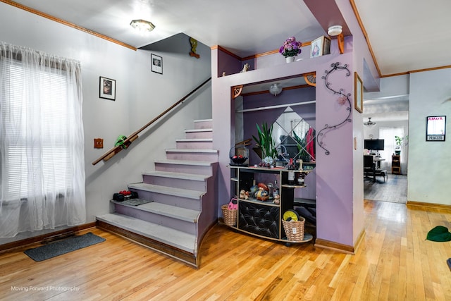 stairway with ornamental molding, baseboards, and hardwood / wood-style flooring