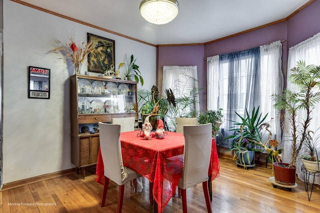 dining space featuring a notable chandelier, crown molding, baseboards, and hardwood / wood-style floors