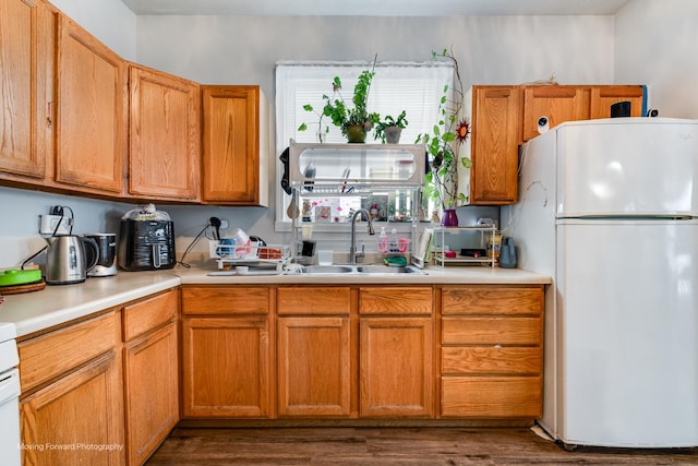 kitchen featuring dark wood-style floors, freestanding refrigerator, brown cabinets, and light countertops