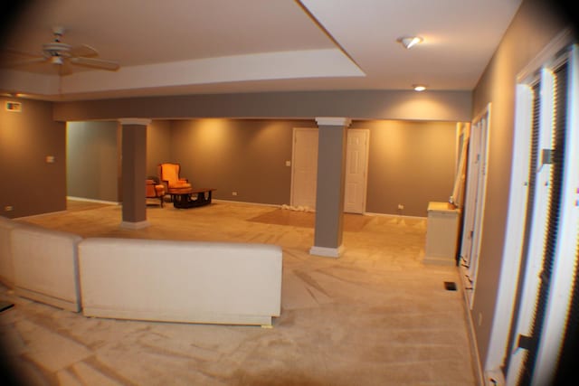 finished below grade area featuring light carpet, ceiling fan, and baseboards