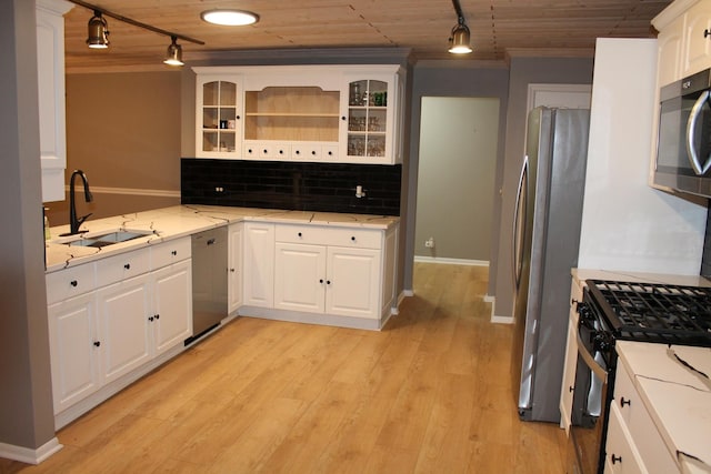 kitchen featuring decorative backsplash, light wood-style flooring, glass insert cabinets, appliances with stainless steel finishes, and a sink