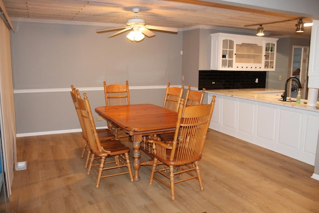 dining room featuring light wood-style floors, ceiling fan, baseboards, and ornamental molding