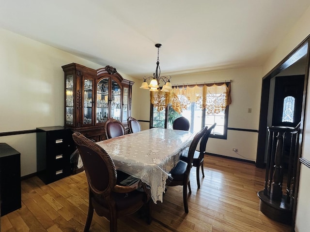 dining room with baseboards, light wood-type flooring, and a notable chandelier