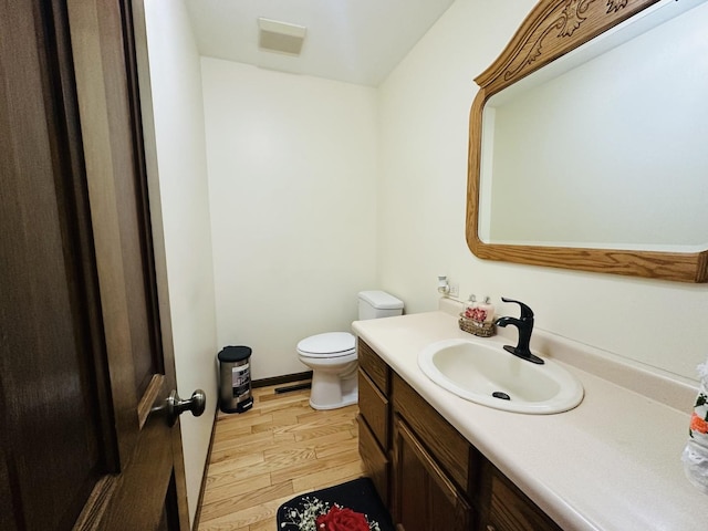 bathroom featuring toilet, wood finished floors, and vanity