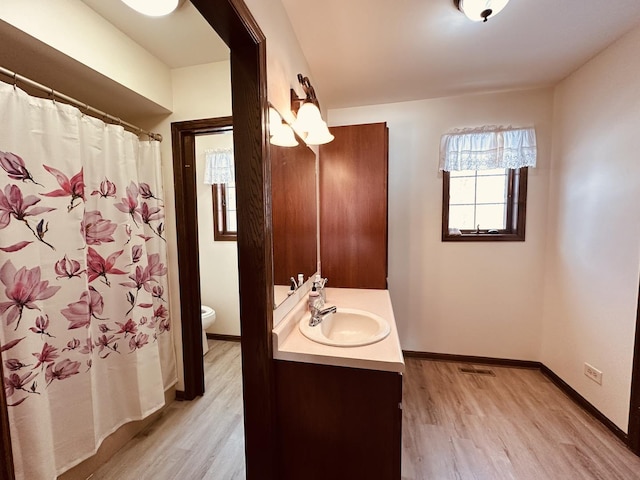 full bathroom with visible vents, baseboards, toilet, wood finished floors, and vanity