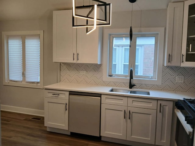 kitchen with range with gas stovetop, stainless steel dishwasher, white cabinetry, a sink, and baseboards