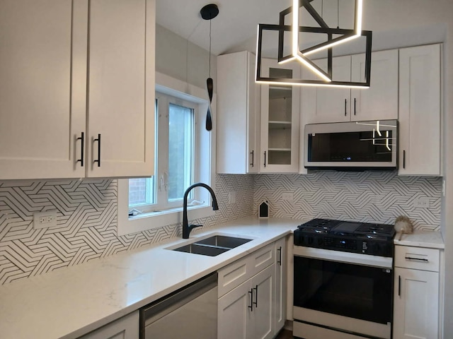 kitchen with appliances with stainless steel finishes, white cabinetry, a sink, and decorative backsplash