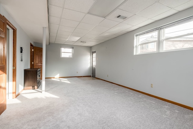 carpeted empty room with a paneled ceiling, visible vents, and baseboards