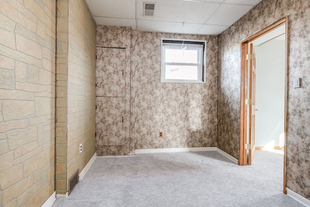 empty room featuring a drop ceiling, carpet flooring, visible vents, and baseboards