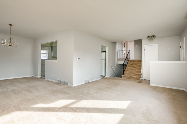 empty room featuring stairs, a notable chandelier, visible vents, and light colored carpet