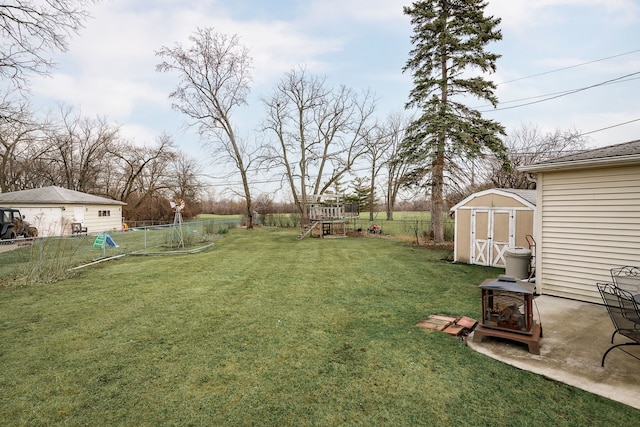 view of yard featuring a storage shed, a fenced backyard, an outdoor structure, a patio area, and a playground