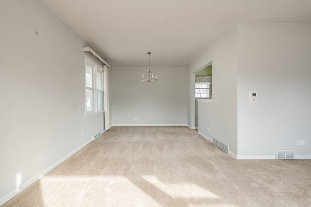 spare room featuring light carpet, baseboards, visible vents, and an inviting chandelier