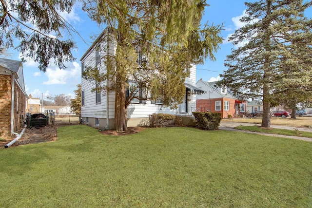 view of side of home with fence and a yard