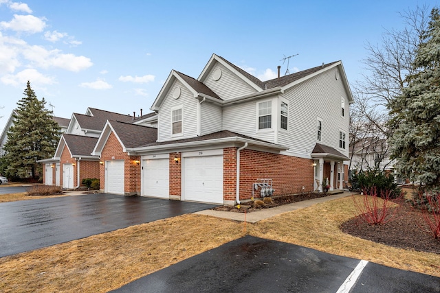 view of front of house featuring aphalt driveway, brick siding, and an attached garage