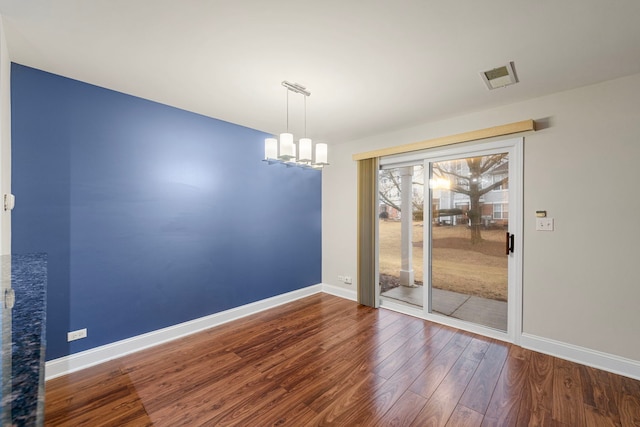 unfurnished dining area with a notable chandelier, baseboards, visible vents, and wood finished floors