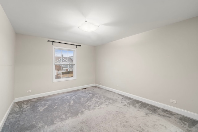 empty room with carpet floors, visible vents, and baseboards