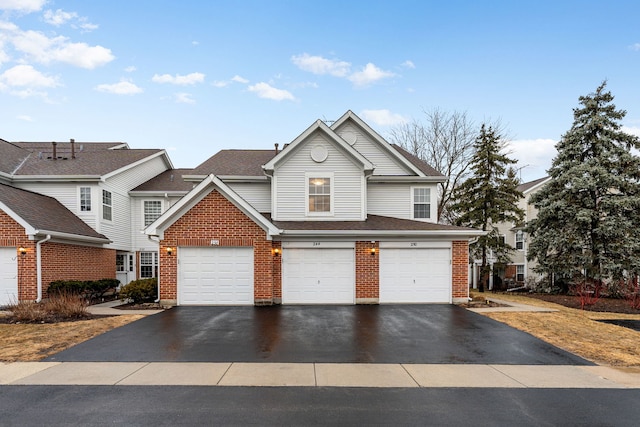 view of front of property featuring a garage, brick siding, driveway, and roof with shingles