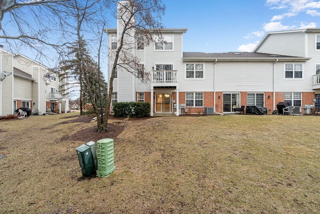 view of front of house featuring a front yard, brick siding, and central air condition unit