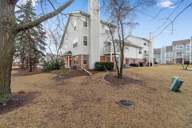 exterior space featuring central AC unit, a chimney, a residential view, and brick siding