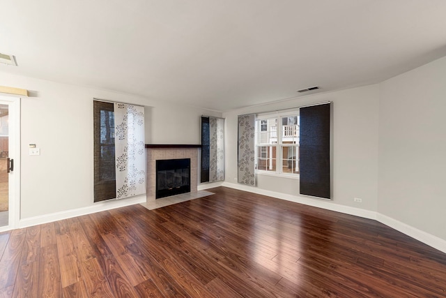 unfurnished living room featuring a fireplace, wood finished floors, visible vents, and baseboards