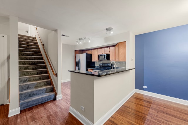 kitchen featuring range with electric stovetop, wood finished floors, refrigerator with ice dispenser, and baseboards