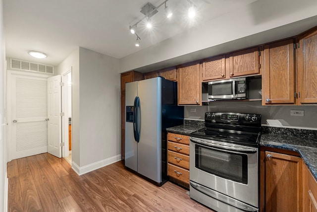 kitchen featuring stainless steel appliances, light wood-style flooring, brown cabinetry, and visible vents