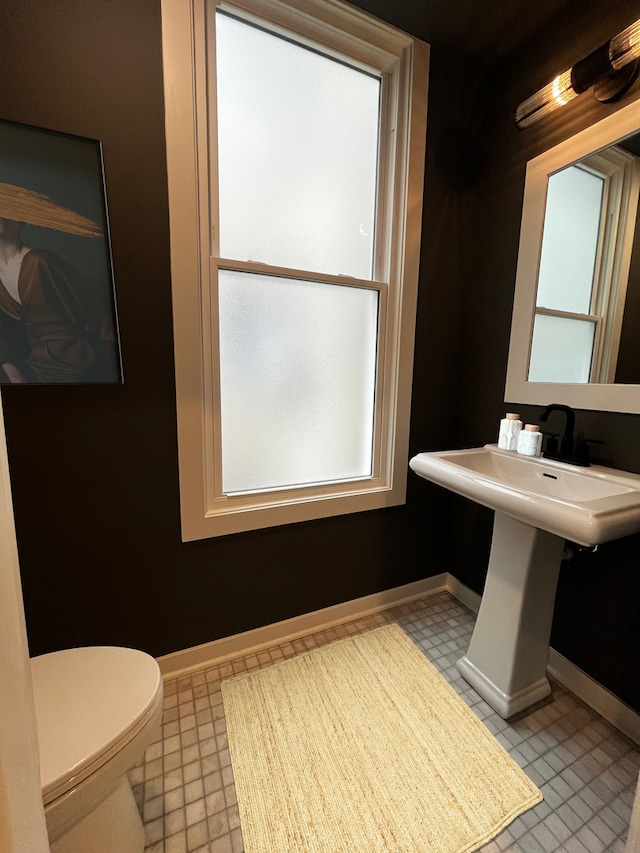 half bath featuring toilet, baseboards, and tile patterned floors