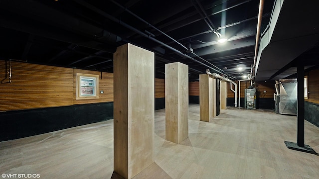 unfinished basement featuring water heater and wood walls