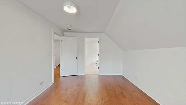 additional living space featuring visible vents, baseboards, vaulted ceiling, and wood finished floors