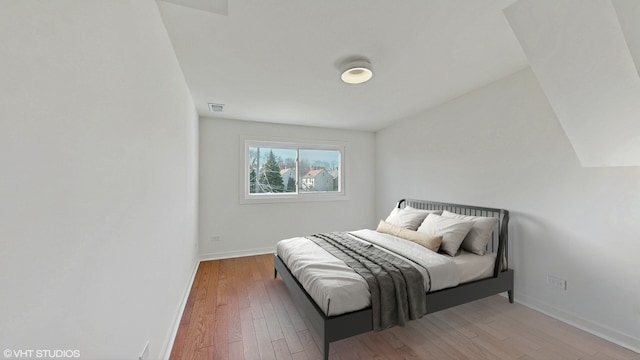 bedroom with wood-type flooring, visible vents, and baseboards