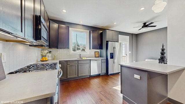 kitchen featuring stainless steel appliances, tasteful backsplash, light countertops, and dark wood-style floors