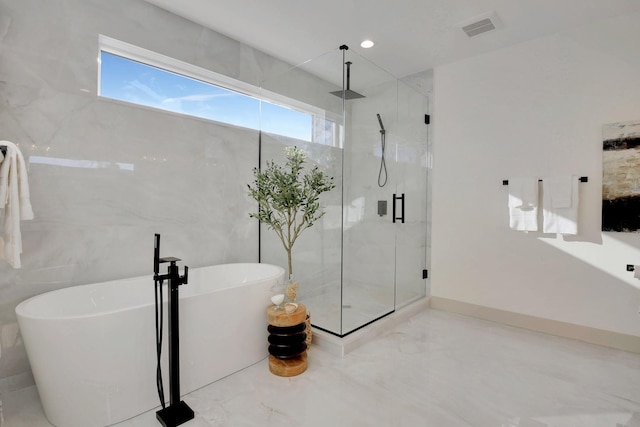 full bath with visible vents, marble finish floor, a freestanding bath, a shower stall, and tile walls