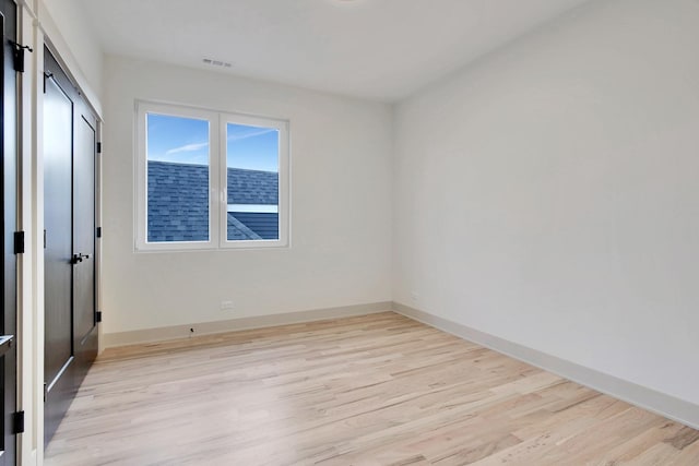 empty room with light wood-style floors, baseboards, and visible vents