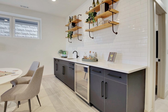 bar with beverage cooler, a sink, visible vents, decorative backsplash, and wet bar