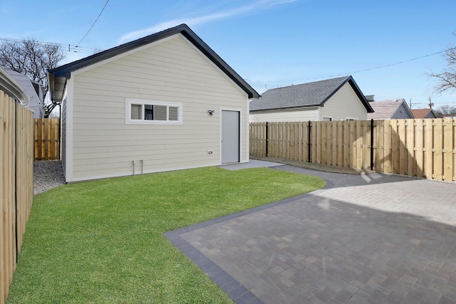 rear view of house featuring a patio area, a fenced backyard, a lawn, and an outdoor structure