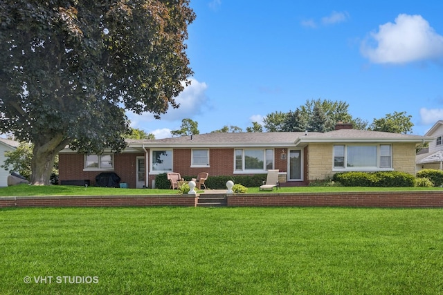 ranch-style house with brick siding, a chimney, and a front lawn