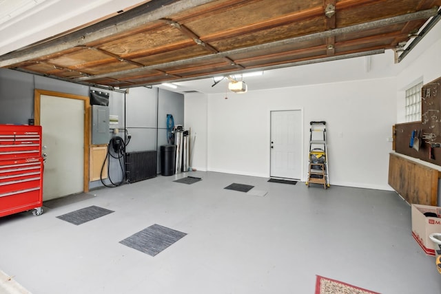 garage featuring electric panel, baseboards, and a garage door opener