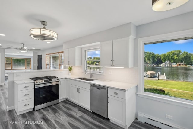 kitchen featuring stainless steel appliances, a baseboard heating unit, white cabinets, a sink, and a peninsula