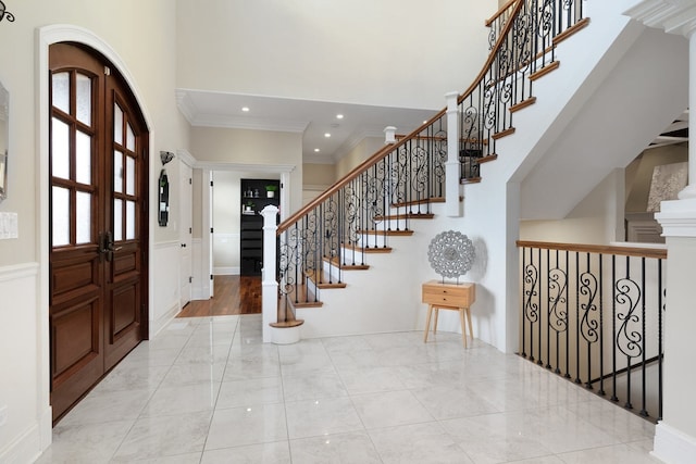 tiled entryway featuring ornamental molding, stairway, a towering ceiling, and recessed lighting