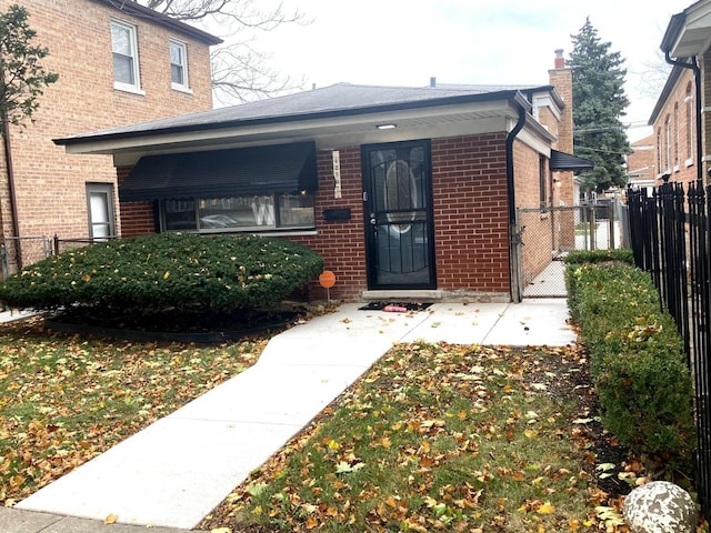 entrance to property with a chimney, a gate, fence, and brick siding