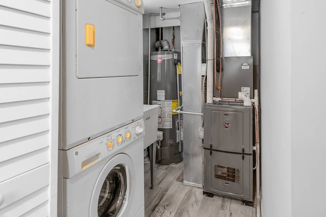 laundry area with laundry area, gas water heater, wood finished floors, and stacked washer / drying machine