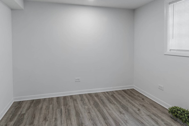 empty room with a healthy amount of sunlight, wood finished floors, and baseboards