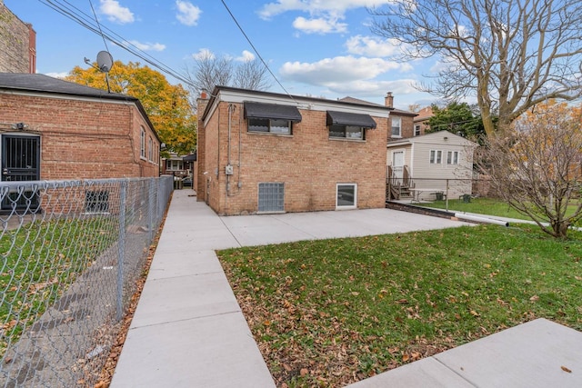 back of house featuring brick siding, a yard, a chimney, a patio, and fence