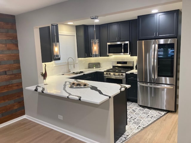 kitchen featuring stainless steel appliances, light wood finished floors, a sink, and decorative backsplash