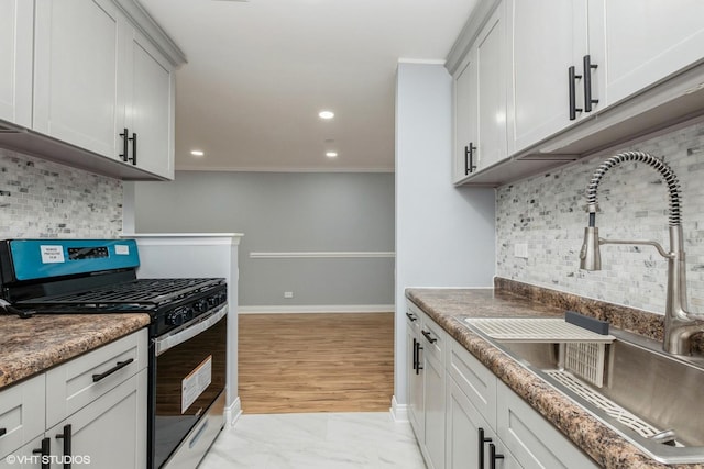 kitchen featuring marble finish floor, recessed lighting, gas stove, a sink, and baseboards