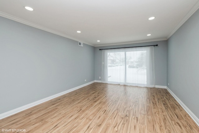 empty room featuring light wood-type flooring, visible vents, crown molding, and baseboards